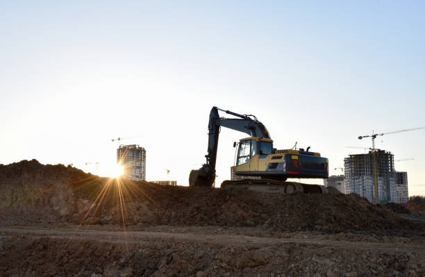 istock Excavator during earthmoving at construction site on sunset background. Backhoe digs ground for underground sewage and water pipes. onstruction machinery for excavating 1271796242