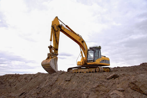 istock Excavator working on earthmoving at open pit mining on sunset background. Backhoe digs gravel in quarry. Construction machinery for excavation, loading, lifting and hauling of cargo on job sites 1271797831
