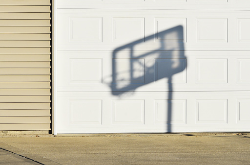 Shadow of basketball backboard and hoop on the garage door.