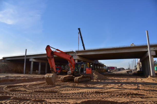 istock Excavator working at construction highway ramps and bridgeworks. Roundabout and traffic bridge construction. Road work on traffic highway, road intersection junction and freeway. Bridge project works 1271801924