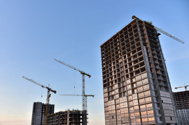 Construction of a new multi-storey building. The facade building with windows and balconies. Tower crane working at construction site. Modern residential building architecture background