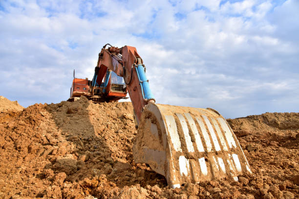 Excavator working on earthmoving at open pit mining. Backhoe digs gravel in quarry. Construction machinery for excavation, loading, lifting and hauling of cargo on job sites