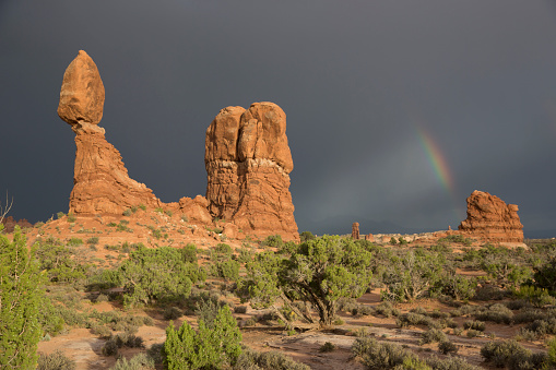 Rainbow forming behind the Balanced Rock of Arches National Park.