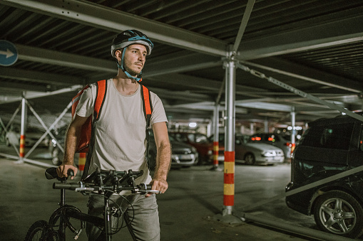Pizza delivery man with bicycle in parkade