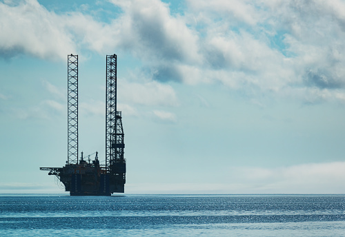 A jackup offshore oil drilling rig is ready for transport on the deck of a heavy lift vessel.