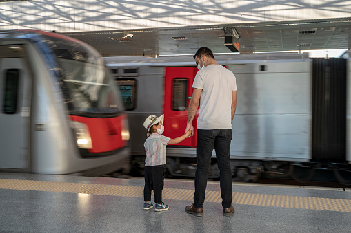 Oğlunun elini tutan baba metroya binmek için metro istasyonunda bekliyor. Metronun geçiş anında, ayakta bekleyen baba ve oğulun fotoğrafı çekildi.