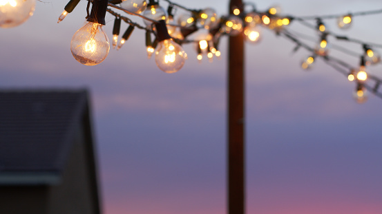 String of lightbulbs hanging over a patio with a house in the background