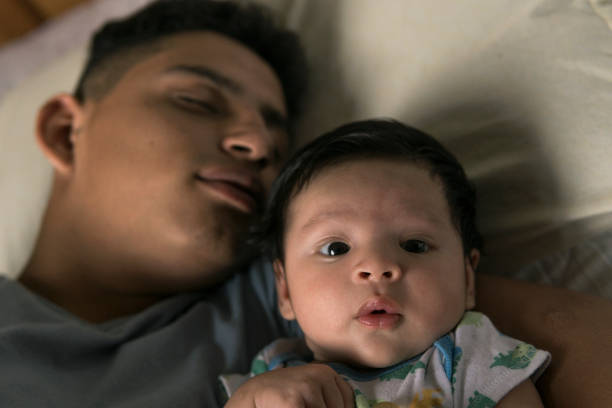 asleep young parent and his serious baby