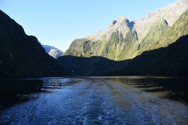 View of the dramatic shadows while boating on the waters of the remote Doubtful Sound fjord on the South island of New Zealand.