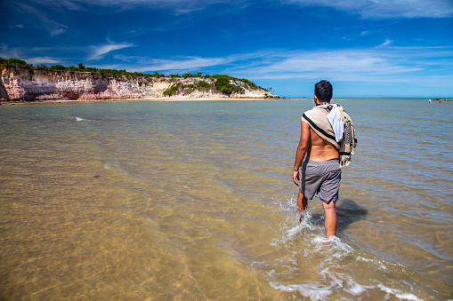 man walking on the beach water at Cumuruxatiba, Bahia, Brazil