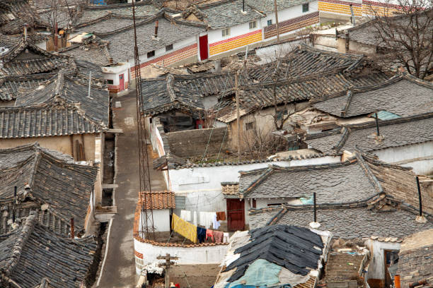 Flat layered stone roofs and Tiled roofs can be seen from the street corners of Kaesong, North Korea.