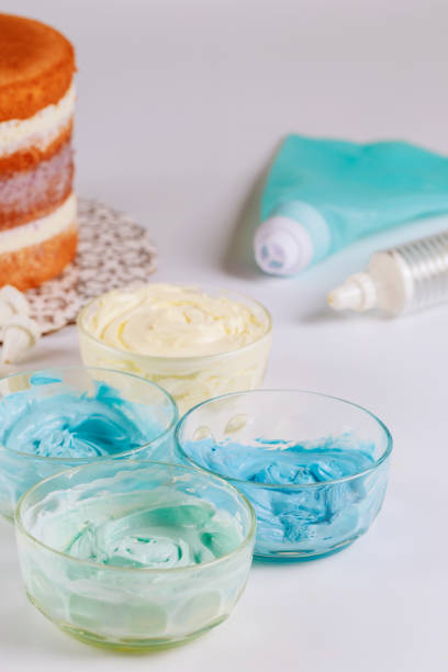 istock White an blue icing in bowls with round sponge cake. 1271859205