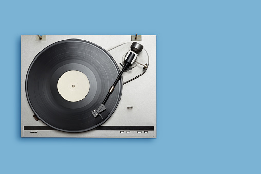 Vinyl player with long play or LP record on blue background. Top view, copy space.