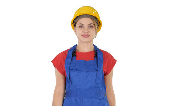 istock Young woman in yellow hardhat walking on white background 1271865744