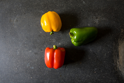Colourful capsicums red, green and yellow on a black background