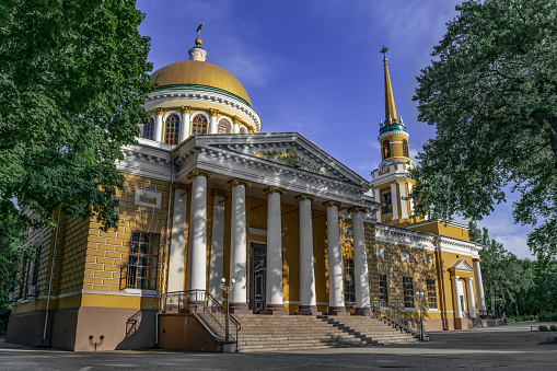 Saviour's Transfiguration Cathedral in Dnipro (Ukraine). Yellow building of the orthodox church on a background of a blue sky among green trees on a summer day