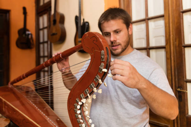 istock Young instrument maker tuning harp at studio 1271870460