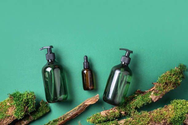 Green glass bottle of shampoo, soap, conditioner on green background with natural moss over bark, wood. Top view, copy space. Blank label for mock-up. Skin care, organic body treatment, spa concept. botella de vidrio verde de champú, jabón, acondicionador sobre fondo verde con musgo natural sobre corteza, madera. vista superior, espacio de copia. etiqueta en blanco para maqueta. cuidado de la piel, tratamiento orgánico del cuerpo, concepto de spa