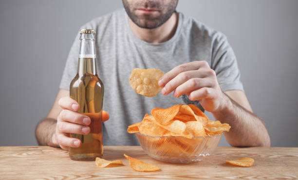istock Caucasian man with tasty potato chips and beer. 1271873300