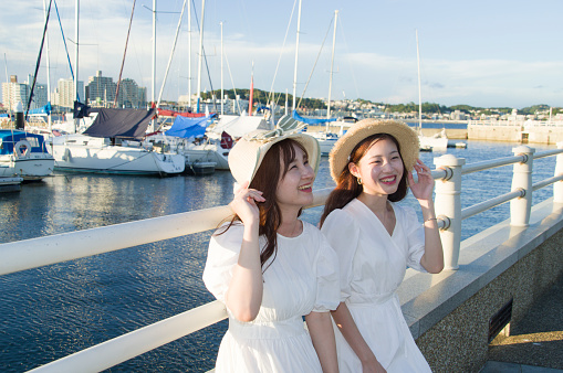 Two women resting at the yacht harbor at dusk