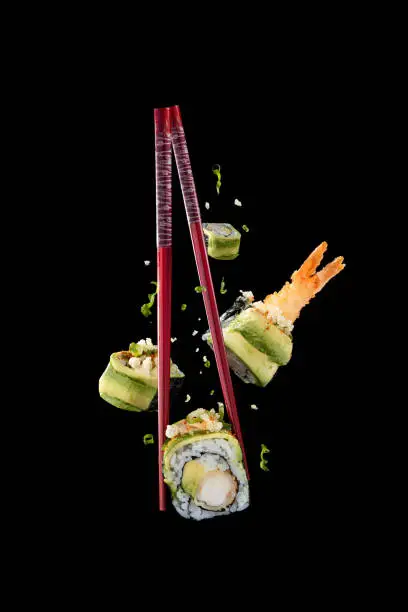 Tempura prawn and avocado sushi flying though the air with chopsticks