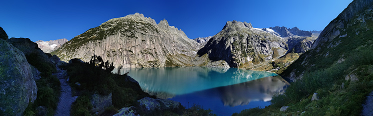 Gelmersee. Dam in the Swiss alps for Hydro power. Clear Blue lake with clear sky.