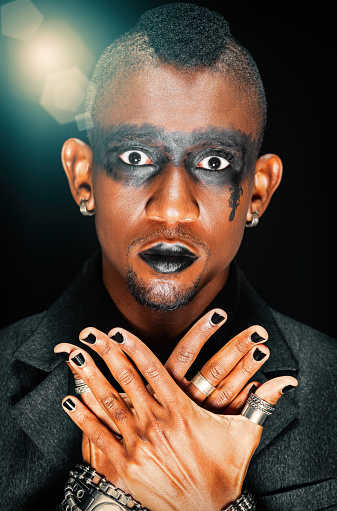 Portrait of a young African man with makeup and contact lenses, gothic style, metal head,