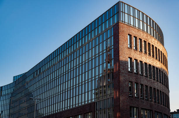 istock Low angle view to modern bank building with glass wall and abstract reflection in sunset golden sunlight 1271887744
