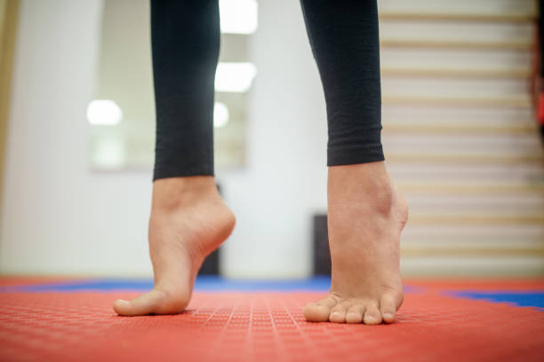 A close up of feet of teenage girl. She taking care of herself and doing flat feet correction exercises in rehabilitation center under the guidance of the physical therapist