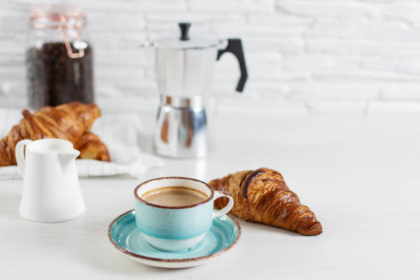 A cup of coffee and ingredients and equipment for making coffee on kitchen table. Morning coffee routine.