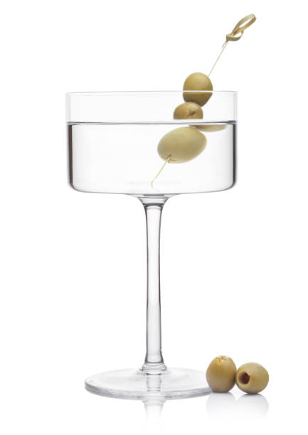 wódka martini gin koktajl w nowoczesnym szkle z oliwkami na bambusa kij ze świeżymi zielonymi oliwkami na białym tle z refleksem. - gin tonic water martini olive zdjęcia i obrazy z banku zdjęć