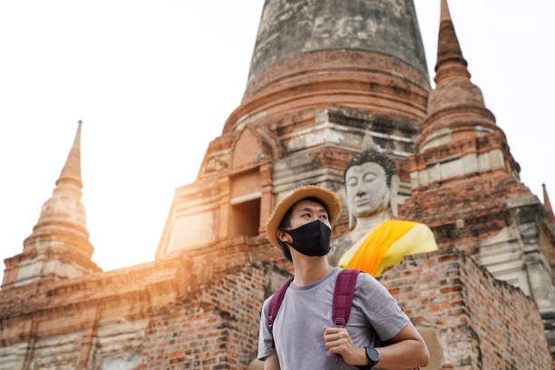 uomo asiatico sorridente dietro la maschera nera mentre si reca ad ayutthaya, in thailandia. indossare una maschera protettiva per prevenire il coronavirus covid-19 - bangkok thailand asia thai culture foto e immagini stock