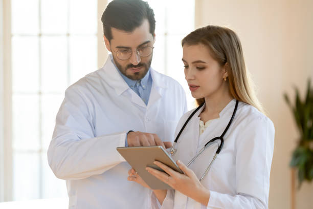 istock Confident doctor and young nurse talking, working together, using tablet 1271898984