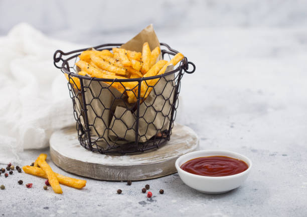 French fries chips in snack bucket with tomato ketchup and pepper on light background. stock photo