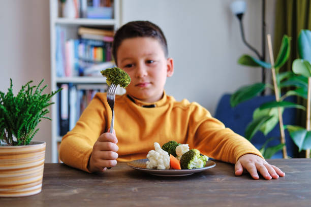 dziecko jest bardzo niezadowolone z konieczności jedzenia warzyw. na jego talerzu jest dużo warzyw. nienawidzi warzyw. - cute disgust carrot caucasian zdjęcia i obrazy z banku zdjęć