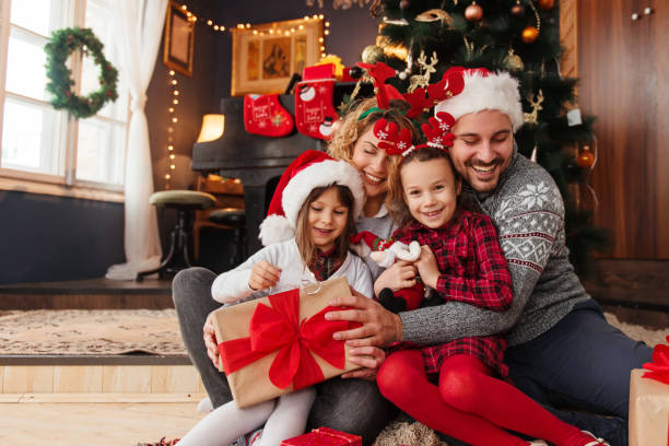 vierköpfige familie feiert weihnachten und tauscht geschenke aus - weihnachten familie stock-fotos und bilder