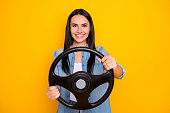 Portrait of her she nice-looking attractive lovely pretty charming cheerful brunet girl turning steering wheel isolated on bright vivid shine vibrant yellow color background