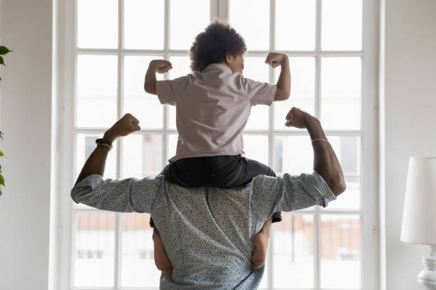 istock African american father with little son on shoulders showing biceps. 1271905919