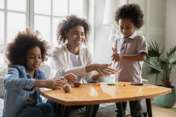 istock Smiling african ethnicity woman creating plasticine figures with kids. 1271905953