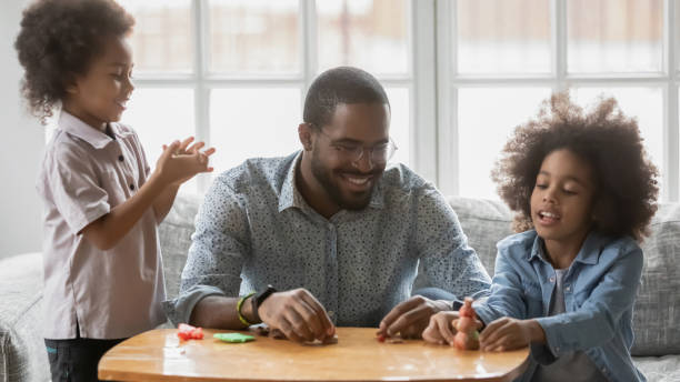 istock Happy young african ethnicity father playing with plasticine with kids. 1271905954
