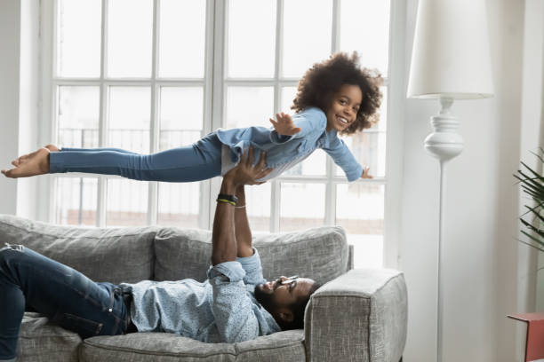 istock Young african ethnicity daddy lifting on hands happy daughter. 1271905960