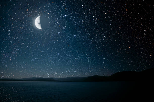 istock moon against a bright night starry sky reflected in the sea. 1271906532