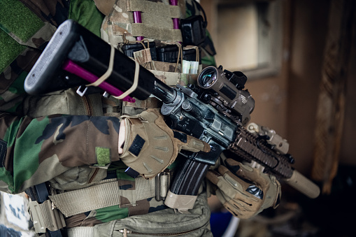 Weapons close-up on a military man standing inside the building and waiting for command