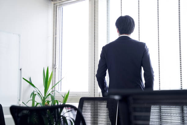 japoński mężczyzna biznesmen patrząc przez okno w swoim biurze - rear view businessman thinking men zdjęcia i obrazy z banku zdjęć