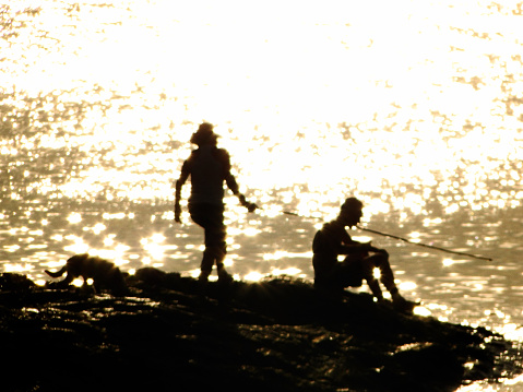 Couple silhouette fishing at golden river coast