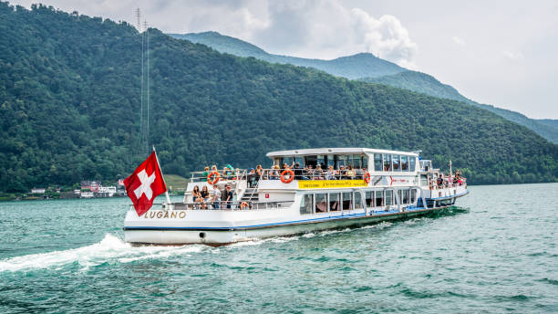 crucero turístico en barco de lugano navegando en el lago lleno de gente y bandera suiza en la parte trasera en el lago lugano ticino suiza - switzerland ticino canton lake lugano fotografías e imágenes de stock