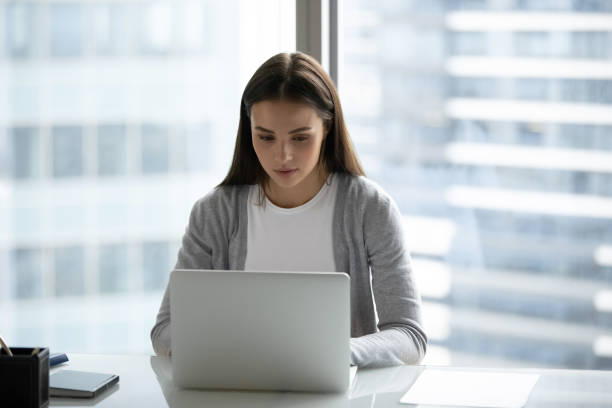 istock Focused young woman working on laptop in modern office 1271916601