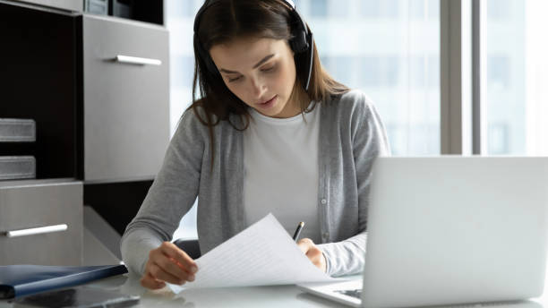 istock Focused businesswoman wearing headset writing notes, using laptop 1271917017