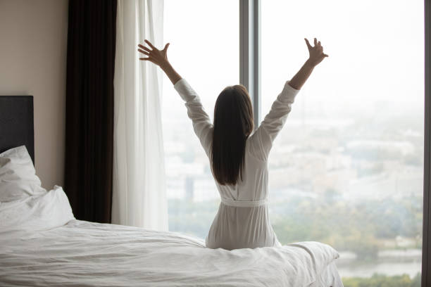 istock Rear view young woman wearing bathrobe stretching after awakening 1271917095