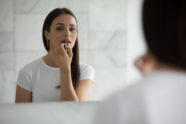 istock Close up mirror reflection young woman applying lipstick 1271917125